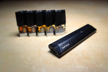 Smok Infinix refillable pod vape pen electronic cigarette with pods filled with e-juices of different shades of orange arranged in a gradient, isolated close upのeditorial素材