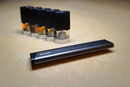 Smok Infinix refillable pod vape pen electronic cigarette with pods filled with e-juices of different shades of orange arranged in a gradient, isolated close upのeditorial素材