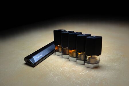 Smok Infinix refillable pod vape pen electronic cigarette with pods filled with e-juices of different shades of orange arranged in a gradient, isolated close upのeditorial素材