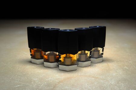 e-juice vape refill pods with liquids of different shades of orange arranged to form a gradient, isolated close upの写真素材