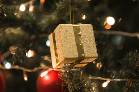 Christmas golden present hanging on a beautiful Chrismas tree surrounded by red shinning ball