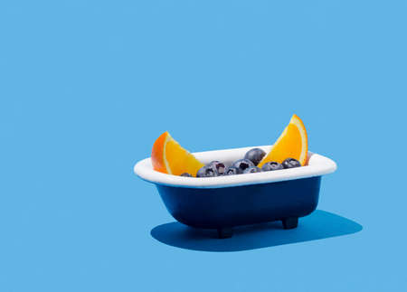 Fresh slices of fruit and blueberries in bathtub on  blueの写真素材