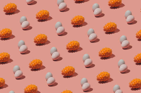 Easter eggs pattern in pink and grey pastel colors with orange kiwano melon fruit with spikes. Easter holiday creative concept background.の写真素材