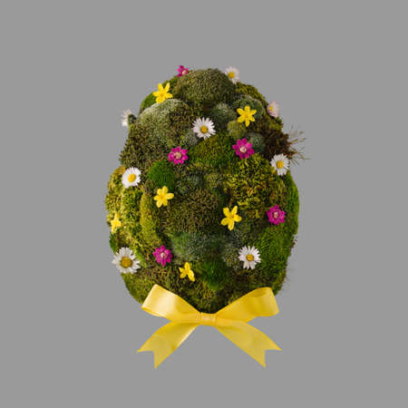 Easter egg shape made of green moss and colorful spring flowersの写真素材