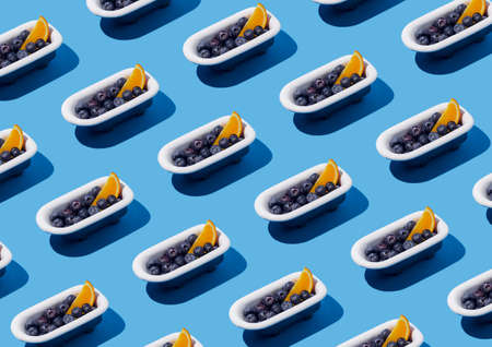Seamless pattern of fresh slices of orange fruit and blueberries in bathtub on blue