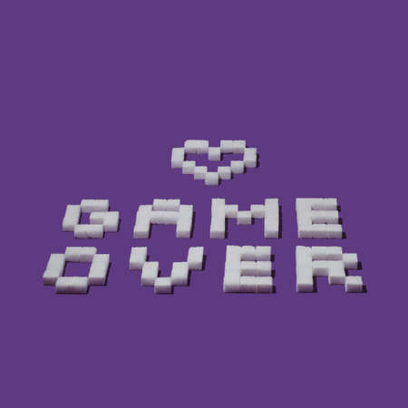 Pixel sign "Game over" and heart made from sugar cubes on purple background. Minimal Vaporware creative love or Valentines concept.の写真素材