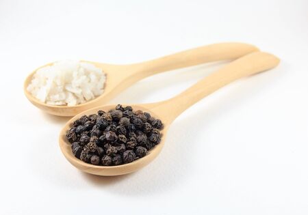 salt and pepper in a wooden spoon. Isolated on white background.の写真素材