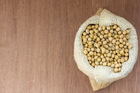Soybean in hemp sack bag on a wooden background.の写真素材