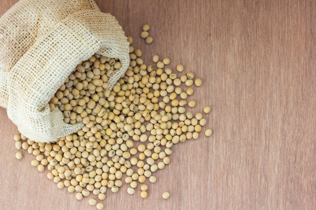 Soybean in hemp sack bag on a wooden background.の写真素材