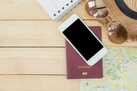 Preparation for Traveling concept, passport, smartphone, sunglasses, noted book, map on a wooden background with copy space.の写真素材