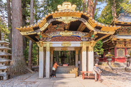 NIKKO, JAPAN - APRIL 16, 2014: A shinto priest sweeps under the Yomeimon gate on April 16, 2014 in Nikko, JP. Founded in 1617, the remains of the first shogun Tokugawa Ieyasu are entombed here.のeditorial素材