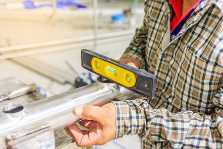 Construction worker using spirit level on the steel pipe for measuring slope of assembled steel pipesの写真素材
