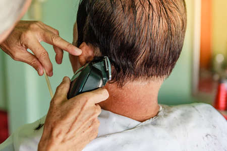 Hair stylist cutting senior asian man's gray hairの写真素材