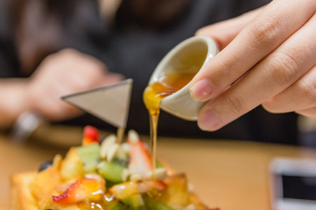 Hand pouring honey in glass jars on honey toast.の写真素材