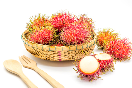 fresh tropical rambutan fruits over basket with spoon and fork on a white background, fruit in Thailandの写真素材