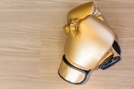 Pair of gold leather boxing gloves on a wooden background, Top view with copy space and text.の写真素材