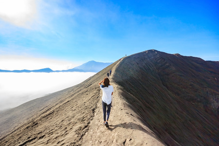 Female tourist walking through on the craters of Gunung Bromo and Sumeru volcanoes in Java, Indonesiaの写真素材