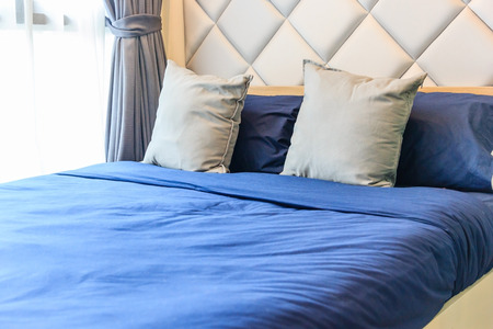 Comfortable bedroom with white bed sheet, blue pillows and turn light on bedの写真素材