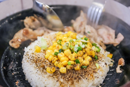 BBQ pork pepper rice with egg in hot black pan, Thai fusion food, Selective focus on center.