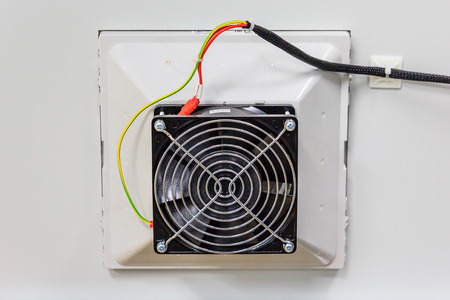 Close-up view of electrical cooling fans seen attached to a data centre's communications cabinet panel, also showing electrical wiringの写真素材