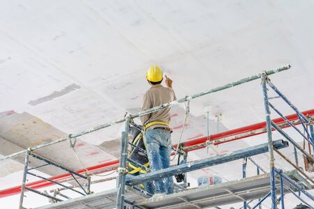 Construction workers on scaffolding tower painting and renovating building floor in construction site.の写真素材