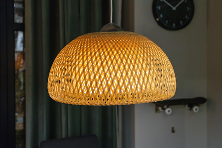 bamboo pendant light lamp hanging above white walls and wall clockの写真素材