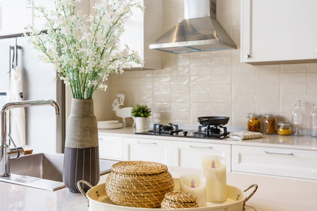 Counter top made in ceramic seen closely with fruits and vegetable on a brown color clay dish next to the modern silver faucet attached to the sink, the silver refrigerator .のeditorial素材