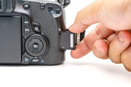 Photographer hand holding SD memory card insert modern DSLR camera, Concept photo of photographer ,...
