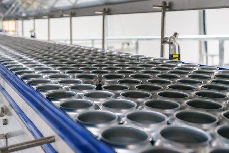 Conveyor line carrying thousands aluminum beverage cans at factory. Concept of industrial growthの写真素材