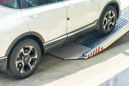 A broken vehicle strapped down to the platform of flat bed tow truck. Roadside serviceの写真素材