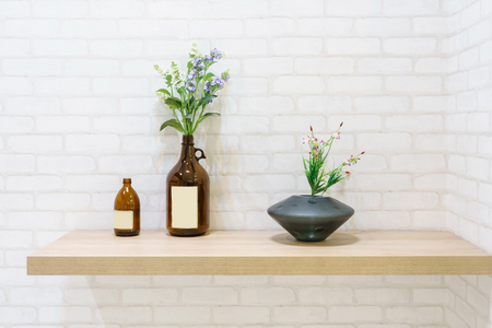 Wood shelf on white brick wall texture background with vintage bottles and vase of flowerの写真素材