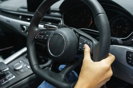Driver's hands on the steering wheel inside of a car