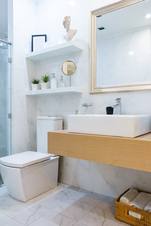 Spacious and bright modern bathroom interior with white walls, a shower cabin with glass wall, a toilet and faucet sinkの写真素材