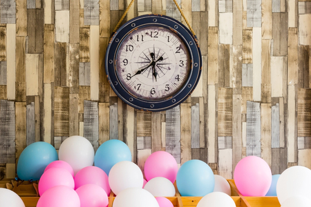 Vintage clock hanging on the wooden wall background with colorful balloons