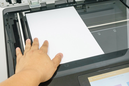 Close-up of young businessman hand operating printer in officeの写真素材
