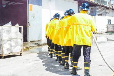 Firefighters using extinguisher and water for fighter fire during firefight training. All hero wearing fire suit for safety under danger situation.の写真素材