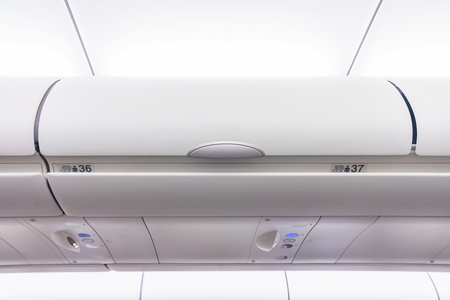 Carry-on luggage in overhead storage compartment on commercial airplane.の写真素材
