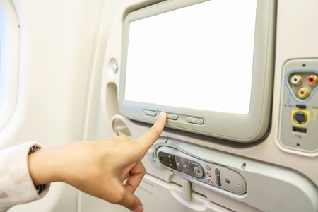 touch screen, close up of a woman pointing finger to white blank LCD screen monitor behind passenger seat in the economy class cabin on the airplane, copy spaceの写真素材