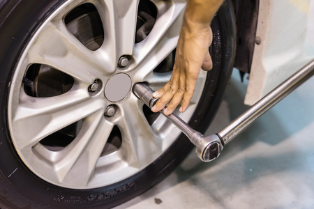 Professional car mechanic changing car wheel in auto repair service.の写真素材
