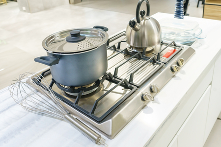 Close-up of stainless steel cooking pot and kettle boiling on gas stove in contemporary modern home kitchen. Selective focus on pot.の写真素材