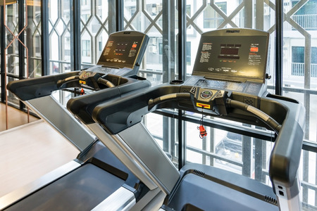 Treadmills set in gym interior. Fitness club with equipment. Sports background with glass windows