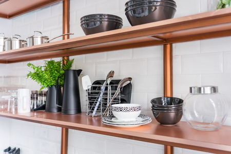 Design of a modern home kitchen in the loft-style. White wall with shelves, trays, jars, mugs, sink. In the background a wall of white brickの写真素材
