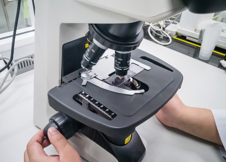 close-up of scientist hands with microscope, examining samples and liquidの写真素材