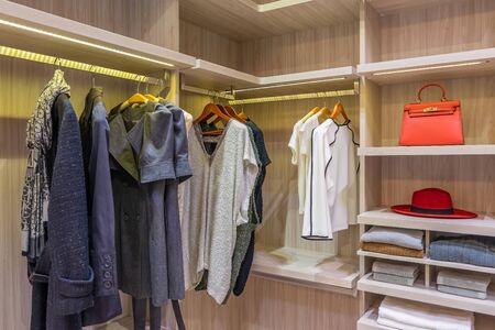 modern wooden wardrobe with clothes hanging on rail in walk in closetの写真素材