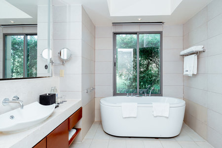 Modern White Bathroom Design with Freestanding Bathtub. Light shine through from a side.の写真素材