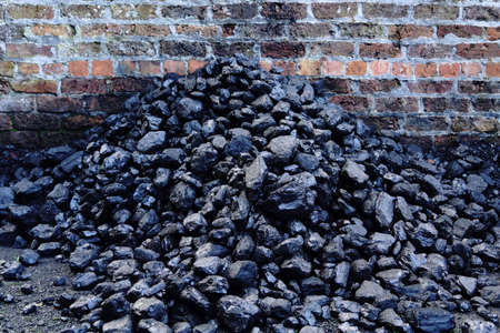 Stack of coal against red brick wallの写真素材