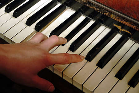 Close-up of female hand playing vintage piano, copy space