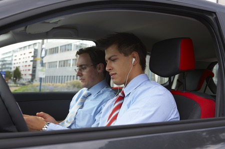 Two young business men are sitting inside a car and enjoing a little break