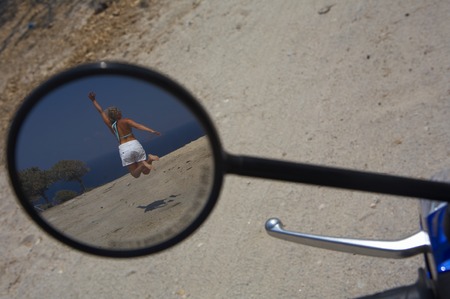 a young woman in bikini seeing through a bike mirrorの写真素材