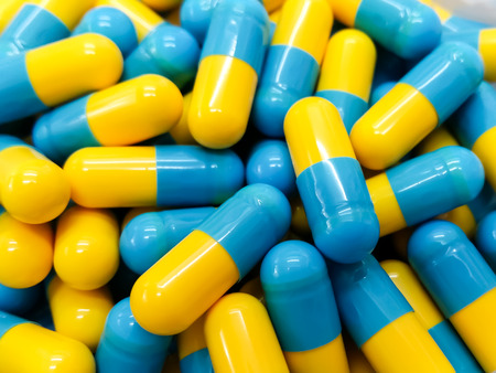 Two tone Medicine Capsules on Stainless Steel drug tray, Yellow Blue Pills and Spatula